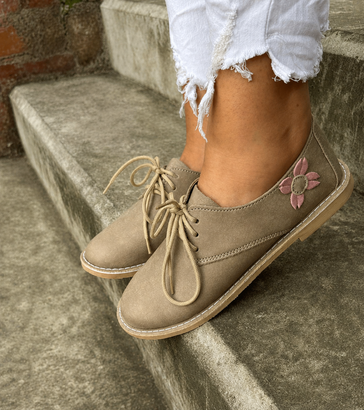 Feather grey vellies with pink flower detail worn on concrete steps — Side Detail